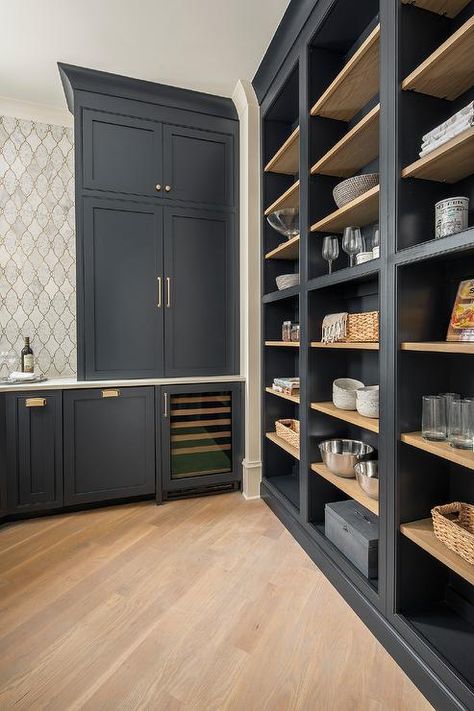 Chic black pantry boasts a diagonal pattern wood floor fitted with a wall of black open cabinetry with blond wood shelves, while blue shaker cabinets donning brass pulls are fitted over a built-in glass front wine fridge. Benjamin Moore Soot Kitchen Cabinets, Open Pantry Wall In Kitchen, Benjamin Moore Soot Paint, Soot By Benjamin Moore, Soot Benjamin Moore Cabinets, Kitchen Cabinet With Shelves, Benjamin Moore Soot Cabinets, Open Kitchen Shelving Ideas Wall Shelves, Pantry Cabinet Colors