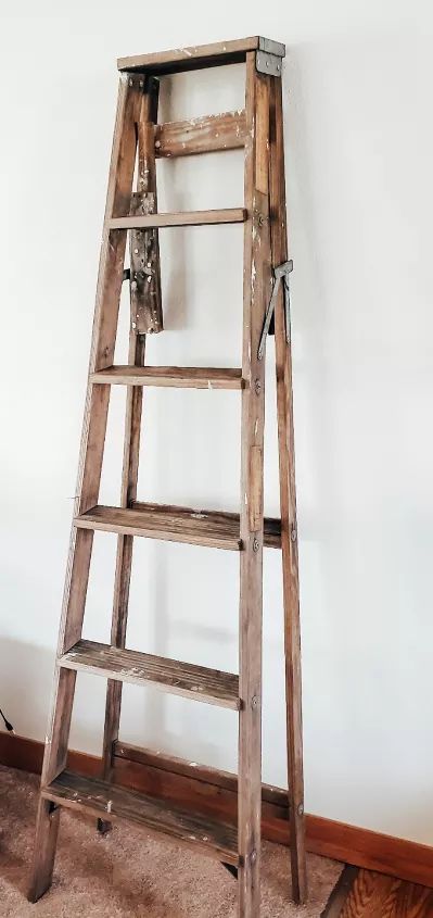 This is an off the wall type project; but it's fun and unique! I have had this wood ladder for a while now. Originally, I painted it and added wood planks as shelves, to create a ladder shelf of sorts. Over the years, the ladder has just been sitting in a corner; but an idea came to me! Why not create a fun piece of decor that's different and not your typical "shelf."That's when I decided a hanging basket plant and some old suitcases could really help turn this old ladder into somethin… Repurpose Blanket Ladder, Things To Do With Old Wooden Ladders, Uses For Old Wooden Ladders, Hanging Wood Ladder From Ceiling, Old Ladders Repurposed, Vintage Ladder Decor, Old Ladder Hanging From Ceiling, Ways To Use Old Wooden Ladders, Old Wood Ladder