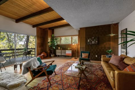 Beyond the front entryway, a living area fills one side of the upper level. Original beamed and wood-clad ceilings mix with vintage wood paneling and light fixtures. #dwell #californianhomes #modernhomesforsale #realestate #midcenturymodernhomes Midcentury House, Vintage Light Fixtures, Chevy Chase, Corner Fireplace, Affordable Housing, California Homes, Mid Century House, Mad Men, Decoration Design