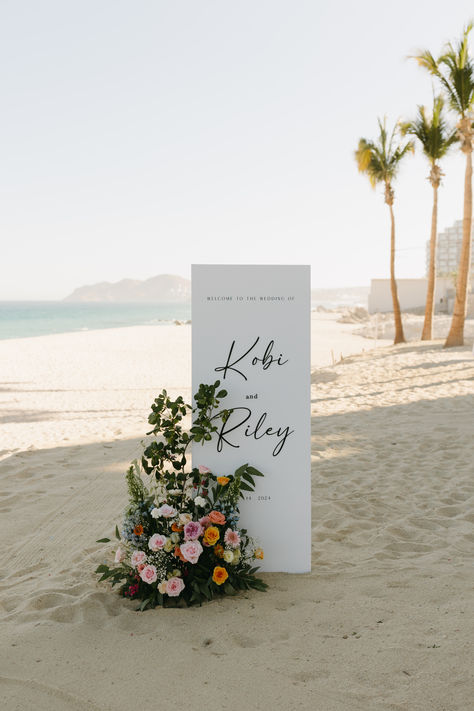 beach wedding welcome sign, wedding signage ideas, floral wedding decor, elegant beach decor, Los Cabos wedding, Garza Blanca wedding, personalized welcome sign, wedding floral arrangement, coastal wedding inspiration, tropical wedding decor, destination wedding details, modern wedding sign, beach ceremony setup Garza Blanca Los Cabos Wedding, Tropical Wedding Sign, Beach Wedding Welcome Sign, Elegant Beach Decor, Tropical Welcome Sign, Wedding Signage Ideas, Colorful Floral Arrangement, Destination Wedding Details, Floral Wedding Decor