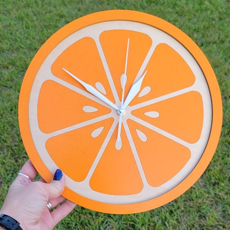 "NOTICE: We are having an issue with our clock hand supplier so, the clock hands may vary just slightly from what is shown. They will still be silent but have less taper to the ends of the hands.  Brighten up your kitchen with this orange slice clock! Made from maple wood and measures about 10.5\" tall. Quality silent sweep Clock movement with white hands." Pink And Orange Kitchen Decor, Food Themed House Decor, Orange Themed Kitchen, Fruit Kitchen Decor Themes, Food Themed Kitchen Decor, Fruit Themed Decor, Orange Fruit Decor, Fruit Home Decor, Fruit Themed Kitchen