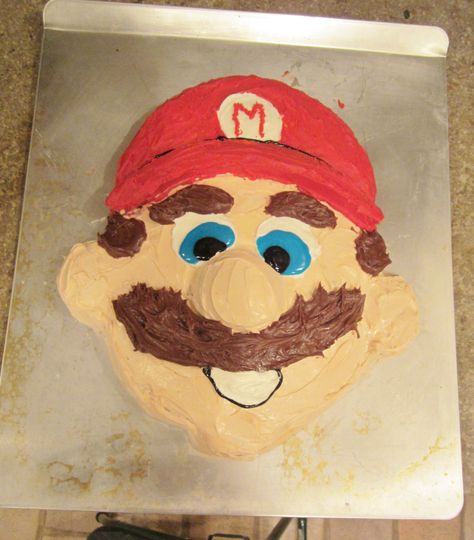 Use two 9" rounds and 3 cupcakes. Use one 9" round for the face and then cut the other to shape for the hat.  Use 3 cupcakes for the nose, ears and chin.  I think it turned out pretty cute! You'll have to buy the red, blue, black and brown frosting's, but you can make the flesh color one for the face by mixing 8 drops yellow, 6 drops red, 2 drops green into a vanilla can of frosting. Mario Face, Colored Frosting, Themed Baking, Face Cake, Flesh Color, Coloured Icing, Bday Cake, Mario Party, The Flesh