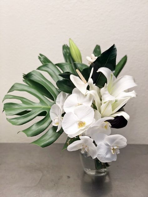 Phalaenopsis orchids, anthirium, and lilies with anthirium and monstera leaf bridal bouquet for a tropical themed wedding. Tropical Orchid Centerpiece, Small Wedding In Hawaii, Modern Tropical Bouquet, Monstera Wedding Bouquet, White Tropical Bouquet, Orchid Wedding Decor, Monstera Bouquet, Orchid Wedding Centerpieces, Orchid Centerpieces Wedding