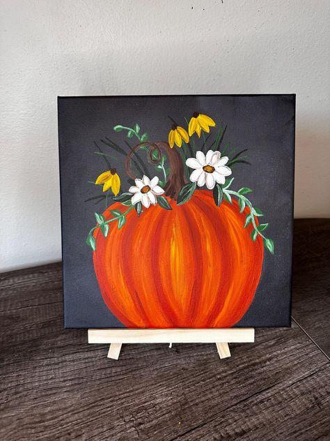 "Harvest Harmony" is a beautifully hand-painted canvas that captures the essence of autumn. The artwork features a vibrant orange pumpkin, richly detailed with subtle shading and highlights, surrounded by a harmonious arrangement of white daisies and bright yellow wildflowers. The dark background creates a striking contrast, making the colors pop and adding depth to the composition. This piece is perfect for adding a touch of seasonal warmth and charm to your home, making it a standout addition Pumpkin Acrylic Painting Easy, Still Painting Ideas, Thanksgiving Pumpkin Painting Ideas, Thanksgiving Painting Ideas Easy, Fall Scenery Paintings Easy, Fall Pumpkin Paintings On Canvas, Mini Fall Paintings, Fall Theme Painting Ideas, Turkey Paintings On Canvas Easy