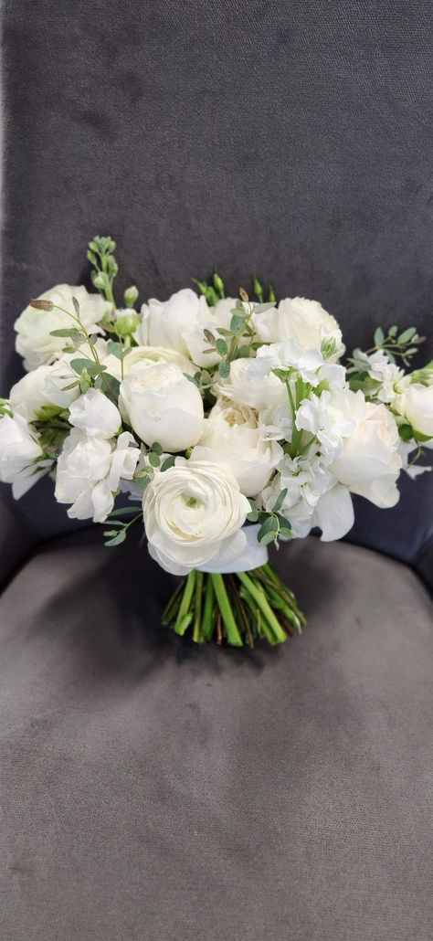 Stunning large bridal bouquet with white florals and a touch of greenery. Flowers such as white ranunculus, white lizzy, white stock, white garden roses, with a sprinkle of gunnii euc. #bridalbouquet #bride #bouquet #whiteflowers #whitebridalbouquet #whitewedding #rose #ranunculus Renuculas White, White And Greenery Bridal Bouquet, Simple White Bridesmaid Bouquet, Ranaculus Wedding Bouquet, Classic Bridal Bouquet All White, White Runuculous, Ranunculus Bouquet Wedding, Bride Bouquets White Elegant, White Ranunculus Wedding Bouquet