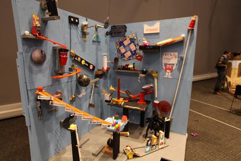 A Rube Goldberg machine is a deliberately complex contraption in which a series of devices that perform simple tasks are linked together to produce a domino effect in which activating one device triggers the next device in the sequence. Task Ideas, Goldberg Machine, Rube Goldberg, Rube Goldberg Machine, Domino Effect, Mish Mash, Image Search, Toys