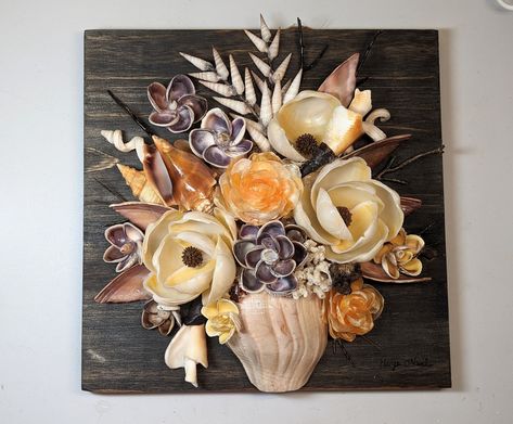 Hand picked seashells from Florida come together to create this one of a kind three dimensional bouquet of flowers. So much to see from every angle. A variety of seashells including orange jingle shells, buttercup Lucien, orange horse conch, Florida fighting conch, augers, worm snails, White coral and black soft coral. All shells are artfully glued onto a 10" by 10" wood backing. Can be hung on the wall or placed on a shelf or desk with the included stand. Flowers From Shells, Things To Do With Shells, Sea Shell Art Projects, Conch Shell Decor, Jingle Shells, Seashell Centerpieces, Shell Bouquet, Seashell Wall Decor, Seashell Flowers