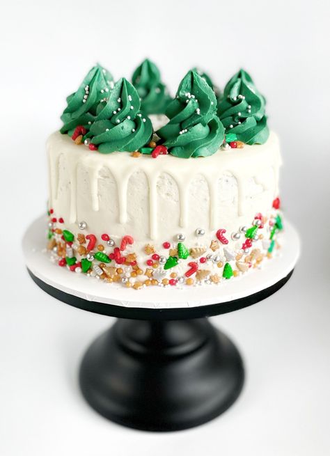 If you love dressing your Christmas Treeyou're going to love making this Christmas DIY cake kitDescription 'Winter PineDIY Cake KitDress this cake like you would dress your xmas treeSprinkle it in a bit of dazzleForest green buttercream perfect for making a delicious Xmas tree toppingA drizzling of white chocolate drip for decadence and our custom Christmas sprinkle mix that has all the Christmas favouritesThis cake is super easy to whip up and will definitely impress your family Cake With Trees On Top, Christmas Drip Cake Ideas, Christmas Cake Buttercream, Christmas Cakes Decoration, Christmas Buttercream Cake, Christmas In July Cake, Christmas Cake Decoration Ideas, Christmas Cakes Ideas Decoration, Christmas Smash Cake