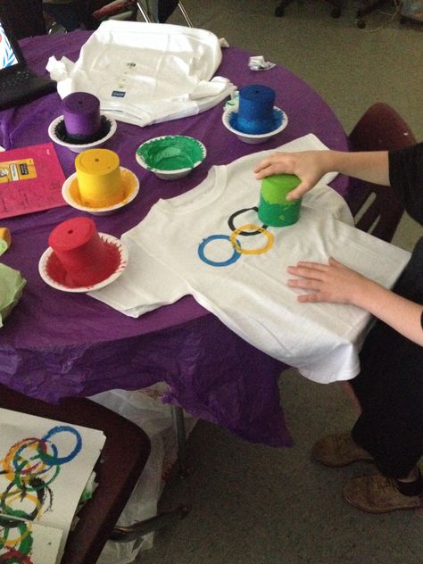 Classroom Olympics!  We're learning about Greece along with gods and goddesses. We decided to create T-shirts for the class to wear. They were spit into 5 teams (one for each ring color) on the back we wrote their names in the color of their team. (Fabric markers or sharpies) One the front, we put the Olympic Rings using coozies. Believe it or not, they have another purpose! ENJOY! Daycare Olympics Games, Olympic Crafts For Adults, Olympic Opening Ceremony For Kids, Funny Olympics Games, Nursing Home Olympic Games, Olympic Games Activities, Kid Olympic Games, Kids Olympics Party, Olympic Games For Seniors