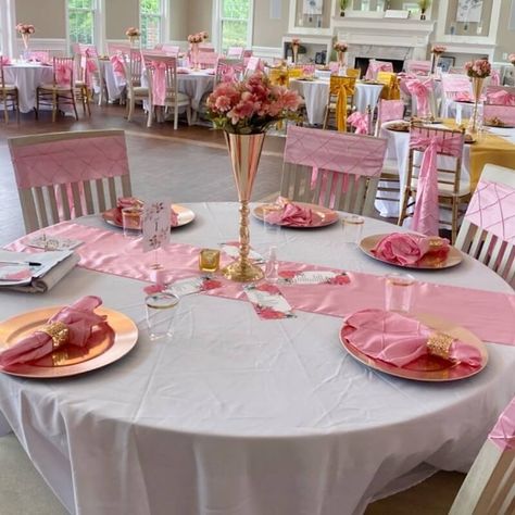 Impart a truly magnificent allure into your party by creating eccentric pink & white tablescapes. Give your tables a lavish drape with white tablecloth and pink satin runner atop and beautify the chairs with pink pintuck sashes. Make your table setting look top notch by arranging gold chargers, pink pintuck napkins, and wine cups and elegantly showcase a pretty pink flower arrangement in gold trumpet vase to exude a brilliant refreshing appeal in your tabletop decoration. Pink Flower Arrangement, Event Decor Ideas, Moms 60th, Party Decorations Table, Pink Flower Arrangements, 60th Bday, Gold Chargers, White Tablecloth, Vase Flowers