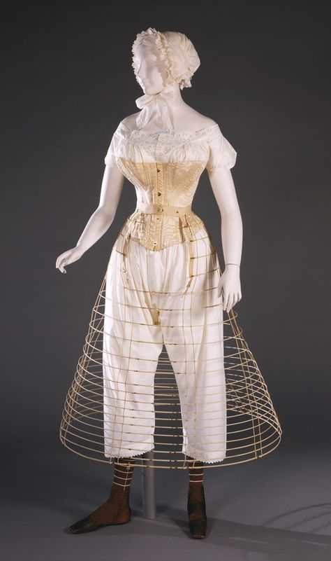 National Underwear Day—This fashionable woman in the 1860s is wearing a chemise and drawers, a corset was gusseted and boned to give a full bust and hips and small waist, a hoop skirt supported a wide skirt, and several smoothing petticoats would also be added. Are you feeling cooler now? Diy Corset, Stockings And Boots, Mannequin Dress, Hoop Skirt, Philadelphia Museum Of Art, Century Clothing, Antique Clothing, Different Dresses, Historical Dresses