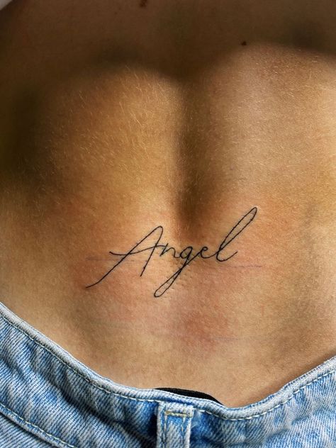 Angle Word Tattoos, The Name Angel Tattoo, Angel Word Tattoo For Women, Angel In Cursive Tattoo, Angel Tramp Stamp Tattoos, Angel Energy Tattoo Cursive, Angel Written Tattoo, Cursive Tramp Stamp, Angel Script Tattoo