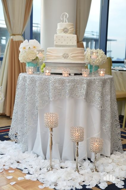 cake table set up but in pink and grey    http://www.recycledbride.com/listing/tablecloths/silver-overlays-1 Cake Table Backdrop Ideas, Simple Elegant Wedding Table Settings, Cake Table Set Up, Silver Table Runner Wedding, White Tablecloth With Silver Overlay, Silver Cake Stand Wedding, Wedding Cake Table Furniture, Lighted Sweetheart Table Skirt, 25th Wedding Anniversary Cakes