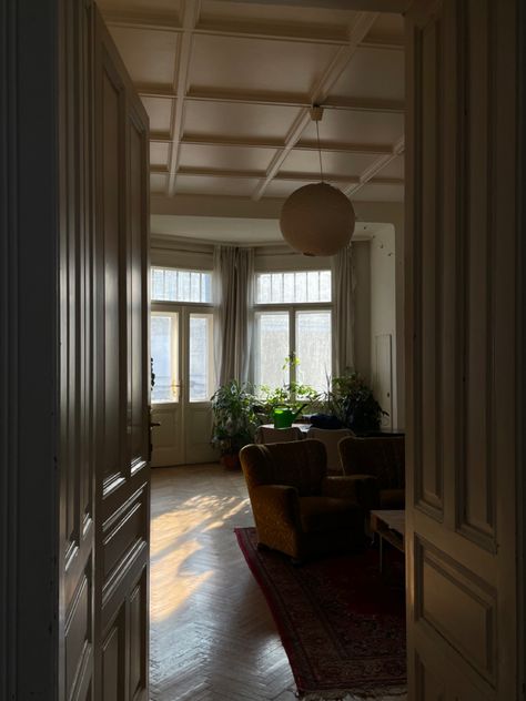 spacious living room in an old timey viennes apartment with high ceilings, yellow brown hardwood floors and wood panel doors. the rising sun creeps in and gives the whole room a golden glow Vienna Apartment, Slow Living, Sunday Morning, Vienna, Apartment