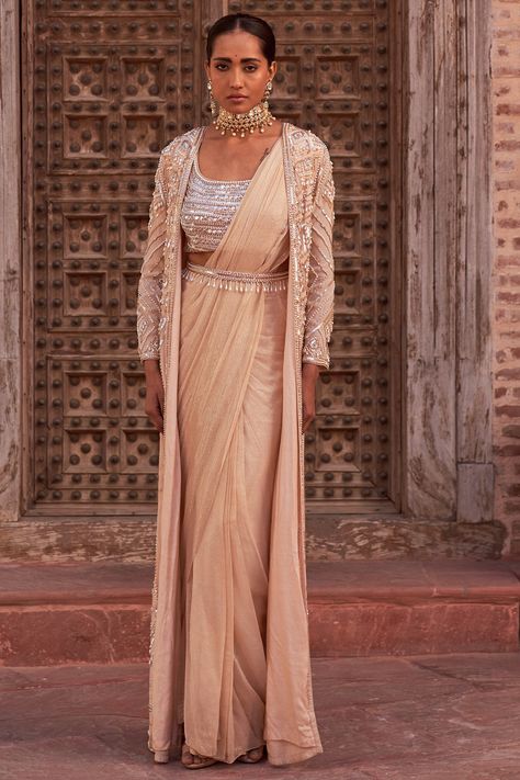 Featuring a champagne cape in crepe base with hand embroidery. It is paired with a matching foil georgette draped saree, a padded blouse having pearl, sequins, and stones embroidery, including an embellished belt. #perniaspopupshop #whatiworewastrending #ppuslove #nidhikashekar #festivewear #champagnecrepegeorgettesaree #sareeset #saree #sareeset embroideredjacketset Stone Embroidery, Blouse Yoke, Embellished Belt, Open Sleeve, Blouse Sleeveless, Color Champagne, Fitted Suit, Silk Embroidery, Fabric Silk