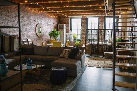 This brick industrial loft is full of plants and pops of yellow. We love the iron accents, the wooden stairs and the string lights on the ceiling. Industrial Apartment, Artist Loft, Brick Loft, Loft Interiors, Living Room Photos, Apartment Aesthetic, Loft Design, Industrial Loft, Loft Apartment