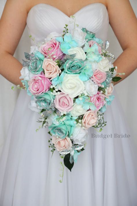 This lovely assortment of Tiffany blue hydrangea, spa roses, candy pink and blush pink roses is bound to turn heads on your wedding day. This lovely cascading brides’ bouquet from the is an absolutely breathtaking arrangement for any bride to be, in any season. Spa roses tipped in silver glitter and silver accents complete the look and add a delicate realism to this beautiful bouquet. This bouquet is 10” wide, 18” long, and is crafted by our in-house florists without using a foam base to anchor Mint Green And Pink Wedding Bouquet, Teal And Light Pink Wedding, Aqua And Pink Wedding, Pink And Blue Wedding Ideas, Tiffany Blue And Pink Wedding, Teal And Pink Wedding, Beach Wedding Flowers Bouquet, Baby Blue Wedding Theme, Fake Wedding Flowers