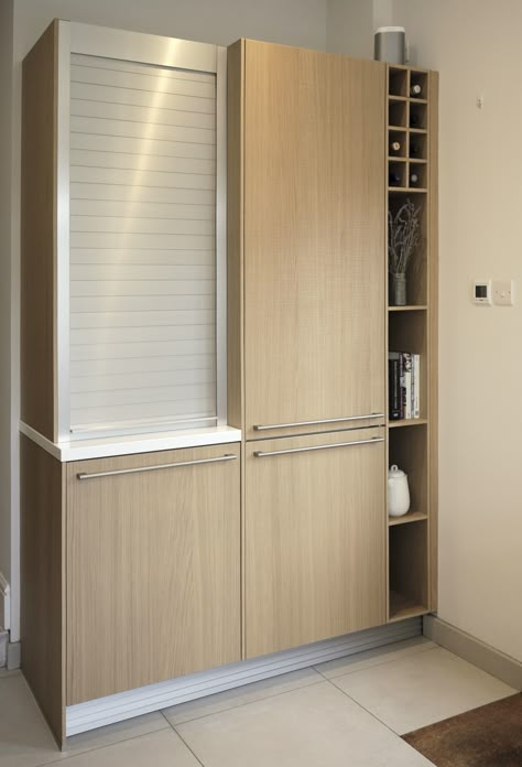 Natural saw-cut oak tall cabinet with stainless steel roller-shutter door and Corian worktop.   #kitchen #cooking #storage #rollershutter #stainlesssteel #oak #veneer #tallunit #cabinet #schuller #next125 Kitchen Roller Shutter Cabinet, Roller Shutter In Kitchen, Rolling Shutter Kitchen, Corian Worktop, Kitchen Shutters, Minimalist Entryway, Stainless Steel Kitchen Cabinets, Top Kitchen Cabinets, Glass Kitchen Cabinets