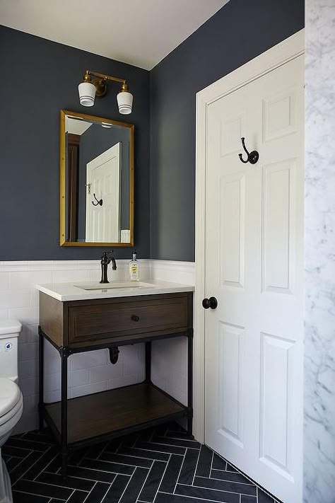 Blue and gray kid's bathroom features upper walls painted dark blue and lower walls clad in white subway tiles lined with a wood and iron washstand and a Restoration Hardware Rivets Medicine Cabinet illuminated by Schoolhouse Electric Irvine Double Sconces alongside a gray slate herringbone tiled floor. Dark Blue Bathrooms, Herringbone Tile Floors, White Subway Tiles, Bad Inspiration, Herringbone Floor, Room Tiles, Boys Bathroom, Downstairs Bathroom, Basement Bathroom