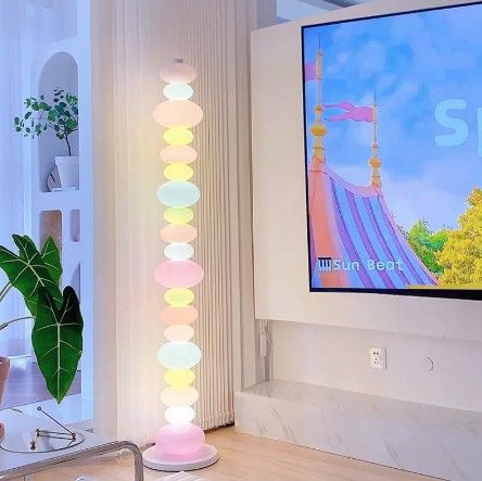 A floor lamp that looks like a candy string necklace, with each piece featuring a different rainbow color, creating a stunning visual display when illuminated.

The body of the lamp features a sleek cold white finish with an iron texture, adding a touch of modernity to its whimsical design. The lamp is crafted with high-quality glass pieces that are not only visually appealing but also easy to clean, ensuring long-lasting durability and easy maintenance. Pebble Floor, Bedroom Table, Glass Floor Lamp, Fancy Lights, Rainbow Glass, Glass Floor, Table Lamps For Bedroom, Estilo Preppy, Led Floor Lamp