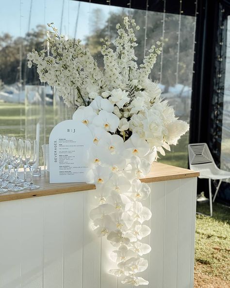 Looking forward to the next wedding season, so we can create some more stunning bar blooms for our beautiful couples. BJ + Joe 🖤 @nedlandsyachtclub Elegant Modern Wedding Reception, Pedestal Wedding Decor, Wedding Bar Design Ideas, Wedding Greenery Ceremony, White Floral Table Arrangements Wedding, Florals On Bar Wedding, Elegant White Floral Arrangements, Flower Arrangements For Engagement Party, Outside Wedding Bar