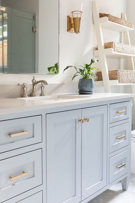 This light blue vanity cabinet is either called spa blue or cotton candy blue. Feel the spa luxury at your home. A simple white countertop and backsplash and ladder shape standing shelf are the elements that make me think about a spa. #bluecabinets #bluecabinetry #bluecupboard #shakerbluecabinets #whitequartz #quartzcountertops #quartztops #whitecountertops #mosaicfloors #mosaictiles #marblemosaictiles #mirrors #lightbluecabinets #palebluecabinets #powderbluecabinets #dustybluecabinets Light Blue Master Bath Vanity, Blue Cabinets Master Bath, White Bathroom Blue Cabinets, Blue Shaker Bathroom Vanity, Bathroom Vanity Blue Gray, Light Blue White Bathroom, Bathroom Light Blue Vanity, Powder Blue Cabinets Bathroom, Light Blue Bathroom Floor Tile