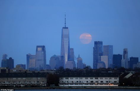 The Moon can be seen glowing red through the clouds over the Manhattan skyline, with One World Trade Center in the distance with the photographer standing in New Jersey Worm Moon, Last Super, March Equinox, Blood Moon Eclipse, Craters Of The Moon, Lookout Tower, Closer To The Sun, Moon Setting, One World Trade Center