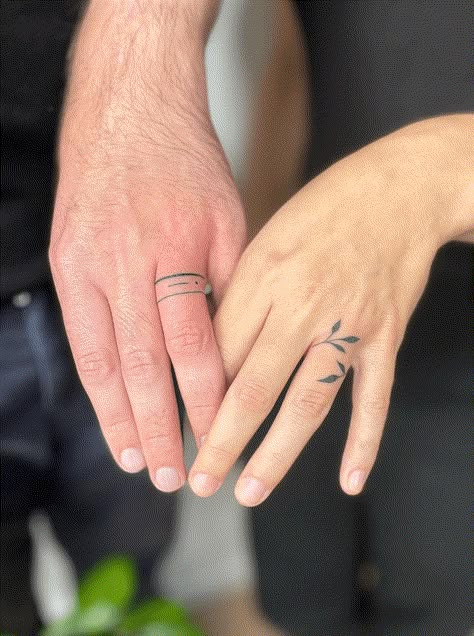 33 Beautiful Wedding Ring Tattoos for Non-Traditional Couples Unique Tattoo Wedding Bands, Ring Tattoo With Ring, Tattoo Around Wedding Ring, Ring Finger Tattoo With Ring On, Ring Tattoo Leaves, Cute Ring Tattoos, Ring Finger Marriage Tattoo, Womens Tattoo Wedding Band, Tattoos Wedding Rings