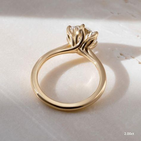 This 2 carat lab grown yellow gold elswin twisted flower engagement ring elevates and enhances the round brilliant cut diamond in a way in which this simple claw prong solitaire features an open basket with six elegant leaves that cradle the center diamond. Handcrafted in Hatton Gardens, London.
 ... daha fazla Claw Engagement Ring, Flower Engagement, Dragon Claw, Flower Engagement Ring, Claw Prong, 2 Carat, Round Brilliant Cut Diamond, Solitaire Engagement Ring, Brilliant Cut Diamond