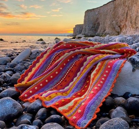 Eleanora Tulley (a.k.a Coastal Crochet) creates stunning crochet designs inspired by her seaside home. The Summer Sunsets blanket perfectly encapsulates blissful warm evenings on the beach, and with it’s fabulous combination of different stitches and soothing colours, it’s a project that you’ll love crocheting from start to finish! One Colour Crochet Blanket Pattern, Crochet Sunset Blanket, Hawaii Crochet Patterns, Tricolor Crochet Blanket, Knitting With Crochet Hook, Pink And Orange Crochet Blanket, Coastal Crochet Blanket, Bright Crochet Blanket, Colourful Crochet Blanket