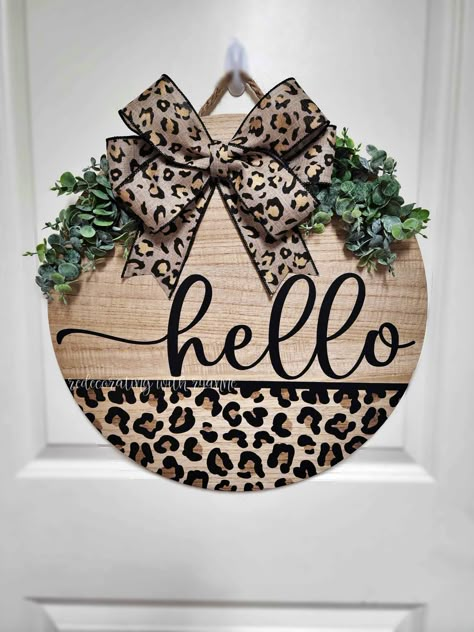 Adorable Cheetah Leopard Print "hello" Door hanger Sign. This product is hand made using premium permanent vinyl, I hand stain the inner part of cheetah spots and then the entire sign is sealed.  The bow is handmade and has two options:  Permanent bow- secured with heavy duty staples or  Interchangeable bow- secured with 4 heavy duty magnets, and allows you to change your bow for holidays, seasons or whenever you're ready for a change. There are 3 listings with different bow options. Check out interchangeable bow options here: https://www.etsy.com/shop/RedecoratewithRyanne?ref=profile_header&section_id=45798628 I invest my love, passion and creative nature into every sign.  If you would like to customize with different color, text, font, etc. Please check out my  Personalized/Custom Door H Every Day Wreaths For Front Door, Leopard Print Door Sign, Leopard Door Sign, Leopard Christmas Wreath, Leopard Print Door Hanger, Round Wood Sign Ideas, Round Wooden Door Hangers, Door Hangers Round, Door Sign Ideas