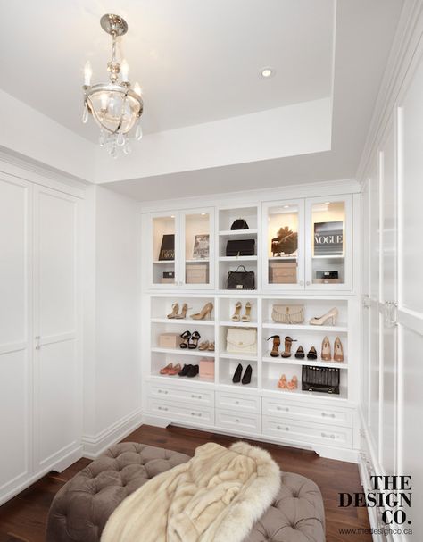 Glam closet features tray ceiling accented with a glass and nickel chandelier with crystal droplets illuminating a brown velvet tufted ottoman flanked by built-in wardrobe cabinets. The back of the walk-in closet boasts glass front display cabinets filled with designer bags illuminated by custom lighting stacked over cubbies filled with shoes and storage drawers accented with glass pulls. Dream Closet Design, Walk In Closet Design, Closet Renovation, California Closets, Closet Decor, Dream Closets, Room Closet, Closet Inspiration, Trendy Bedroom