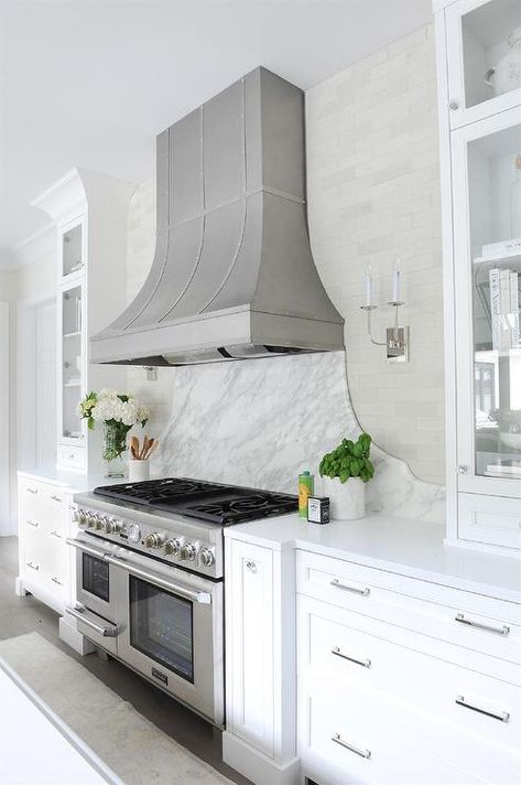 A stainless steel dual oven range sits between white shaker spice cabinets and white drawers and against a curved marble cooktop backsplash. Grey Bathroom Wall Tiles, Dark Stained Wood Floors, Spice Cabinets, Gray Bathroom Walls, Gray Tile Backsplash, Brick Backsplash Kitchen, Marble Backsplash Kitchen, Dual Oven, Quartz Backsplash