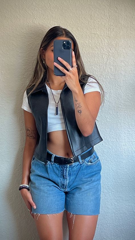 Mirror picture of girl wearing plain white crop top with black leather vest over, jean shorts with black belt, and crystal necklace Cropped Leather Vest Outfit, Vest With Tank Top Outfit, Vest Outfits Denim, Cropped Jean Vest Outfit, Am Concert Outfit, Outfits For The Fair Summer, Black Leather Vest Outfits For Women, Leather Vest Outfit Aesthetic, Button Up Vest Outfits For Women