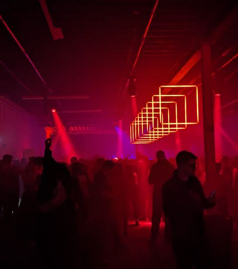 Photo of a darkened crowd in a warehouse made into an event venue lit by a line of square red lights Cyberpunk Bar, Warehouse Rave, Madison + Core + Aesthetic, Rave Core, Environment References, Peggy Guggenheim, Red Light District, Event Lighting, Event Inspiration