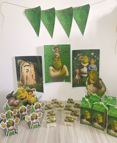 Kit festa personalizado com tema Shrek    Kit contém:  -3 caixinhas milk 2D simples, já com laço incluso.  -3 caixinhas pirâmide pequenas 3D  -10 porta bis duplo 3D  -2 display de mesa - Em papel, com apoio, tamanho máximo de uma A4, variando o tamanho dependendo do desenho.  -3 pôsteres A4  -1 topo de bolo  -1 bandeirola com até 8 letras.      •Após a compra, entre em contato conosco para mandar o nome e idade da criança.  •Prazo de resposta até 24h útil.  •Não trabalhamos aos domingos.    •Pra Shrek