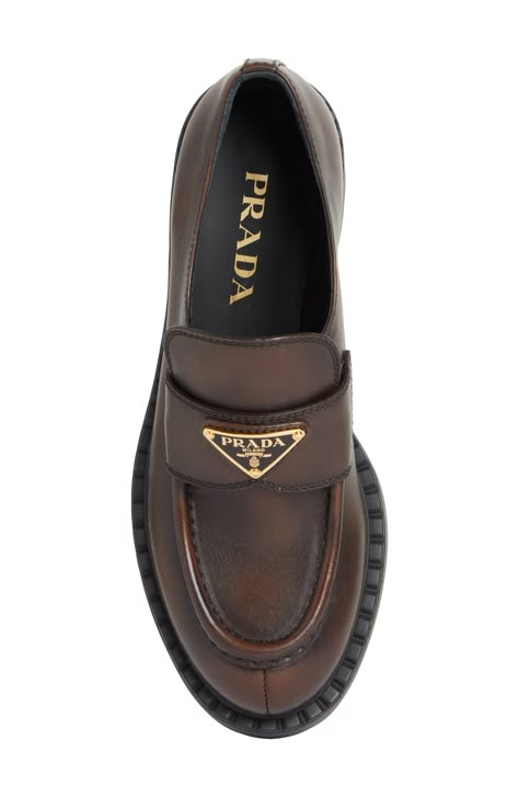 The Prada emblem marks the band of this classic moc-toe loafer lifted on a thick rubber sole and crafted from chocolatey burnished leather. 1 3/4" (50mm) heel Leather upper and lining/rubber sole Designer Shoes Brown Prada Loafers, Womens Loafers Outfit, Prada Loafers Women Outfit, Ysl Loafers, Loafers For Women Outfit, Prada Loafers, Leather Loafers Women, Classy Shoes, Loafer Women