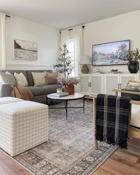 Round white and black coffee table for grey couch stands on a grey vintage rug in this modern farmhouse living room. The table is placed in front of a white cane TV cabinet holding a taupe and white table lamp. Tufted Grey Sofa Living Room, Rug Dark Couch, Gray Couch Tv Room, Grey Couch Natural Living Room, Light Grey Couch Accent Pillows, Dark Grey Couch With Rug, Gray Couch Living Room Rug Ideas, Country Living Room Grey Sofa, Light Gray Couch Green Accents