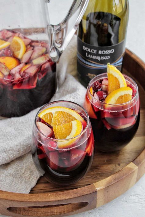 two glasses of sangria in wine glasses. Lambrusco Sangria, Holiday Cocktails Thanksgiving, Winter Sangria Recipes, Superbowl Cocktails, Lambrusco Wine, Winter Cocktail Party, Sparkling Sangria, Red Sangria Recipes, Tequila Soda