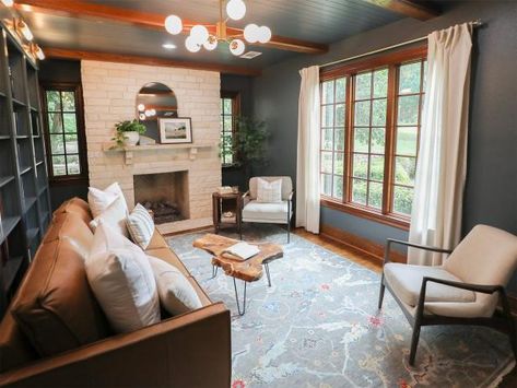 To make her clients' small and disjointed living room feel bigger, No Demo Reno host Jenn Todryk used a moody gray on the ceiling, walls and built-ins to tie every element together. An area rug with lighter gray tones picks up on the paint color and makes the room feel more airy. The creamy stone fireplace, white curtains and matching white chairs provide a break from the dark walls and ceiling. Jenn Todryk, No Demo Reno, Gray Living Rooms, Houses In America, Hgtv Star, Hgtv Dream Home, Decorating Advice, Dark Walls, Outdoor Kitchen Design