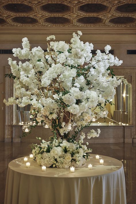 Large all white flower statement arrangement for reception entryway. Wedding tree installation with white florals. Cascading candles hung from white floral arrangement. 

Planning | @aniwolff_
Venue | @plazahotel @plazaparties
Lighting +Production | @bentleymeeker
Photography | @christianothstudio @nelaphotogaphy.co
Florals | @adrianbeventdesign
Flooring | @gotoshout
Rentals | @partyrentalltd White Floral Arrangements, Welcome Table, Hanging Candles, Big Party, Charity Event, Brooklyn Wedding, Tree Wedding, Nyc Wedding, City Wedding