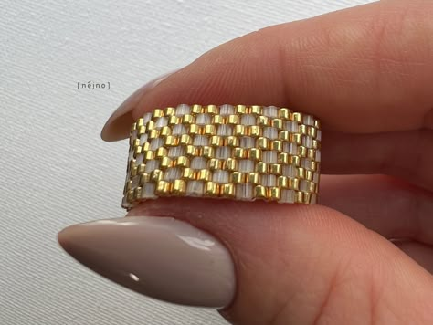 Embrace elegance and flexibility with our custom-made seed bead ring, tailored just for you! Handwoven with precision, this Gold and Satin Minimalist Seed Bead Ring showcases the beauty of japanese seed beads. Ring width: 11 mm (7/16") Crafted with non-stretchy thread; please ensure accurate sizing using our guide below. How to Measure Your Ring Size: - Take a strip of paper (around 1/4 inch or 0.6 cm in width) and wrap it around the base of the finger you wish to measure (if your knuckle is bigger, then measure it instead). Ensure that the paper is snug but not too tight. - Using pen or pencil, mark the spot where the end of the paper overlaps - Unwrap the paper and lay it flat - Use a ruler or measuring tape to measure the distance from the end of the paper to the marked point. This meas Seed Bead Rings Tutorial, Miyuki Ring, Seed Bead Ring, Miyuki Beads Pattern, Beads Ring, Ring Tutorial, Wide Ring, Trendy Ring, Miyuki Beads