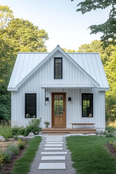 Small metal-clad house with a wooden door and lush garden path. Feast your eyes on the quirky charm, economic genius, and sturdy flair packed into small metal building homes, where industrial meets cozy! White Metal Roof, Small Metal Building, Small Metal Building Homes, Country Home Exterior, Front Door Exterior, Metal Roof Houses, Cottage Houses, Theres No Place Like Home, Door Exterior