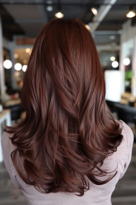 Woman with long, wavy, auburn hair seen from the back in a well-lit salon. Reddy Brown Hair Colour, Dark Brown Hint Of Red Hair, Mahogany Copper Hair Color, Mocha Red Hair, Red Brown Hair Color Balayage, Warm Chestnut Hair, Copper Chocolate Brown Hair, Cherry Brown Hair With Highlights, Cocoa Hair Colour