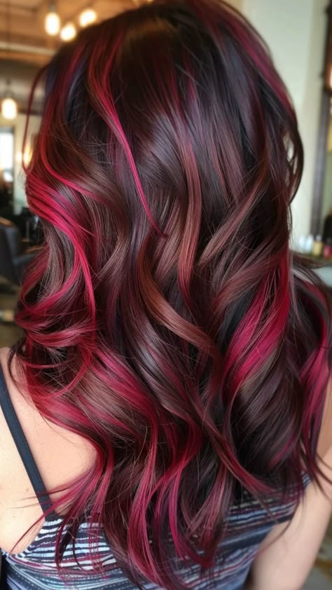 Long, wavy hair with dark brown and vibrant red highlights. Red Streaks In Brown Hair Curly, Red Wine Hair Color With Highlights, Brown Hair With Red Tips, Red And Brown Balayage, Red Highlights And Lowlights, Hair Color Ideas With Red, Red Streak In Brown Hair, Red Highlights In Black Hair, Dark Red And Black Hair