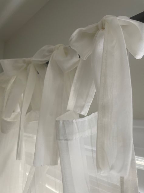 Sheer white curtains hung with extra fabric formed into bows Bows On Curtains, Curtains With Bows, Bow Shower Curtain, White Ribbon Aesthetic, Cortinas Aesthetic, White Bow Aesthetic, Bow Curtains, Curtains Bedroom Aesthetic, Bow Nursery