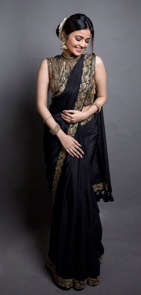 In a gorgeous black & gold color saree and high neck sleeveless blouse design Brocket Blouse Designs, High Neck Sleeveless Blouse Designs, Gold Color Saree, High Neck Saree Blouse, Chiffon Blouses Designs, Bridal Outfit Ideas, Woman In Saree, Black Blouse Designs, Sleeveless Blouse Designs