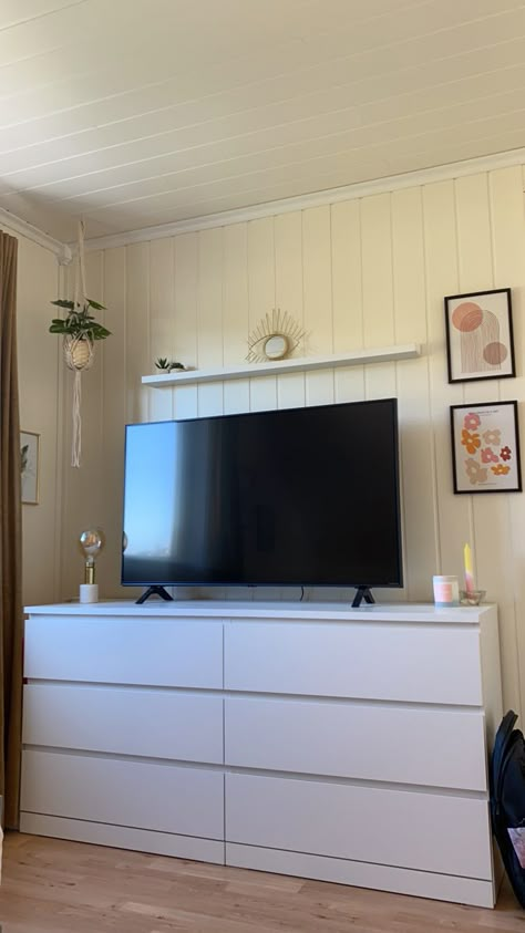 Tv area with a mirror, plants, light and pictures in gold, pink and white tones. Tv Mounted On Wall In Bedroom, Tv On Top Of Dresser Bedrooms, White Dresser With Tv On Top, Small Bedroom Tv Stand Ideas, Tvs In Bedrooms Ideas, Bedroom Inspo With Tv, Room Tv Ideas Bedrooms, Tv Small Bedroom, Tv In Bedroom Ideas On Dresser