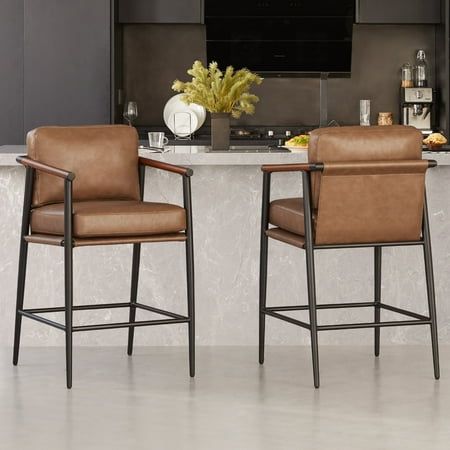 CHITA Mid-Century Modern Barstool  a fusion of sleek metal architecture and a sling-style seat design that effortlessly embodies a minimalist and rustic living aesthetic. The barstool boasts a straightforward square footrest and warm-tone wooden armrests, complemented by soft cushions that invite you to experience unparalleled seating comfort and enduring sturdiness. Crafted to withstand the test of time, the sturdy matte black metal frame ensures durability, while the solid rubber wood armrests Modern Barstools, Kitchen Dining Ideas, Modern Counter Stools, Kitchen Counter Stools, Leather Counter Stools, Dining Ideas, Stools With Backs, Meridian Furniture, Leather Bar Stools