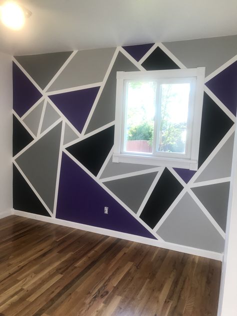 When your son says he would like to use hot rod purple and black for colors in his room...you become resourceful! Made this geometric accent wall with painting tape. Added two shades of grey to the mix. Found this idea on Pinterest!!🖤💜🖤💜🖤 If you paint the tape edges first the same color as your background, your lines will be perfect. Instead of “bleeding” the main color they “bleed” invisible. Do not let dry long, just enough so you can paint your main colors. Tape comes off easy then. Accent Wall Bedroom Purple Grey, Purple And Black Geometric Wall, Tape And Paint Walls, Purple Bedroom Paint Ideas, Blue And Purple Wall Paint Ideas, Black Grey Purple Bedroom, Purple Wall Design Paint, Purple And Grey Room Ideas, Geometric Wall Paint Purple